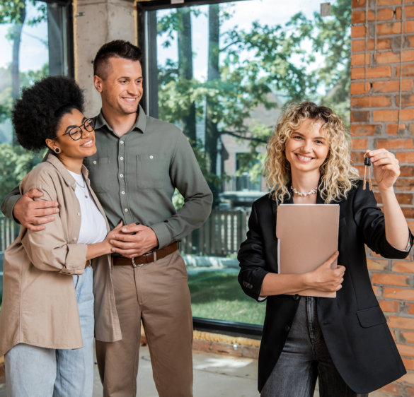 real estate agent with folder holding keys and couple happy